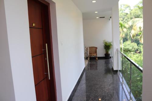 a hallway with a door leading to a balcony at Thenmala Hormuz Inn in Kolattupuzha