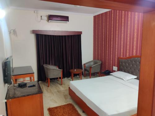 a bedroom with a bed and a desk and a tv at Hotel Chetan International in Bengaluru