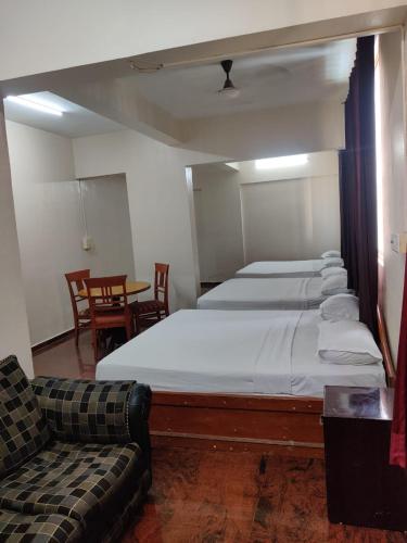 a bedroom with a bed and a couch and a table at Hotel Chetan International in Bengaluru