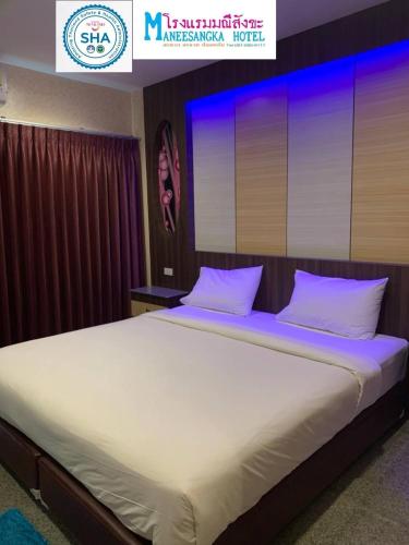 a large white bed in a room with a sign at โรงแรมมณีสังขะ in Sangkha