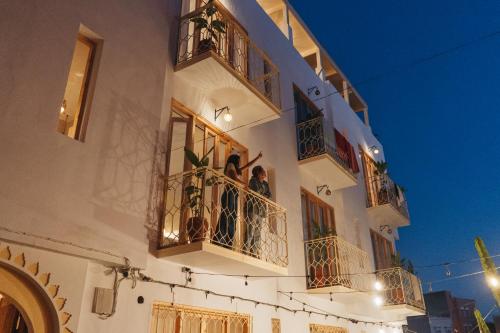 a building with two people standing on the balconies at Blue Waves Boutique Hostel in Tamraght Ouzdar