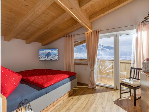 a bedroom with a red bed and a large window at Appartements Morgensonne in Westendorf