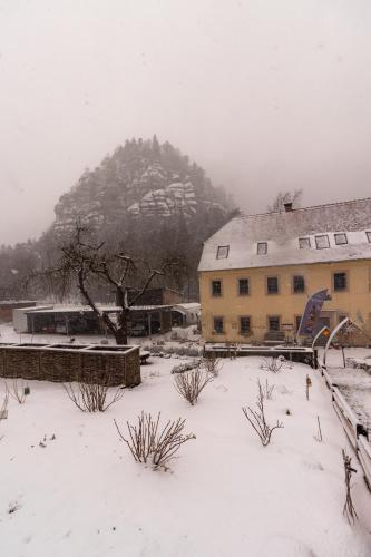 a snow covered yard with a building and a mountain at Holzwerk Oybin in Kurort Oybin