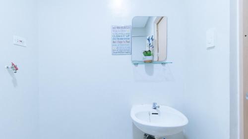 a white bathroom with a sink and a mirror at Jamah's Staycation at SMDC Trees Residences by RedDoorz in Manila