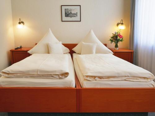 two beds with white sheets and pillows in a room at Hotel Martha Dresden in Dresden