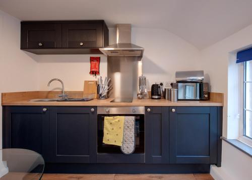 a kitchen with navy blue cabinets and a sink at Donington Cottage Apt 7 in Castle Donington
