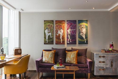a living room with a couch and paintings on the wall at Hotel Indigo Bangkok Wireless Road by IHG in Bangkok