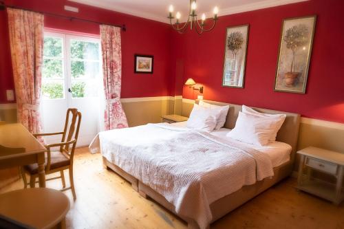 a red bedroom with a bed and a table at Der Linslerhof - Hotel, Restaurant, Events & Natur in Überherrn