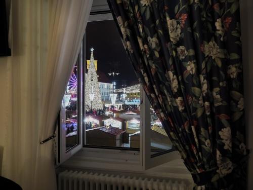 a window with a view of a city at night at ELISABETH HOME Piata Mare in Sibiu