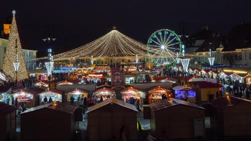 a christmas market with a ferris wheel and christmas lights at ELISABETH HOME Piata Mare in Sibiu