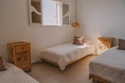 a bedroom with two twin beds and a window at Blue Waves Surf House in Agadir