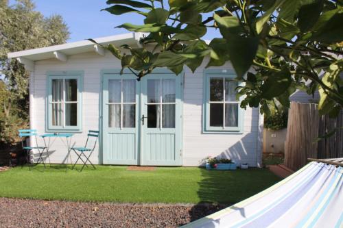 a small white house with a blue door at בקתות שחר in Yonatan
