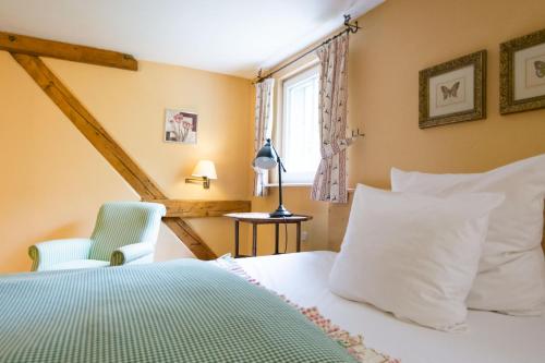 a bedroom with a bed and a chair and a window at Der Linslerhof - Hotel, Restaurant, Events & Natur in Überherrn