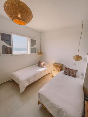 two beds in a room with a window at Blue Waves Surf House in Agadir