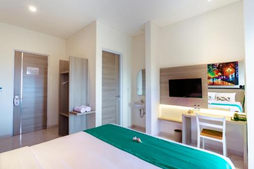 a bedroom with a bed and a desk and a television at Nivasa Nusa Dua in Ungasan