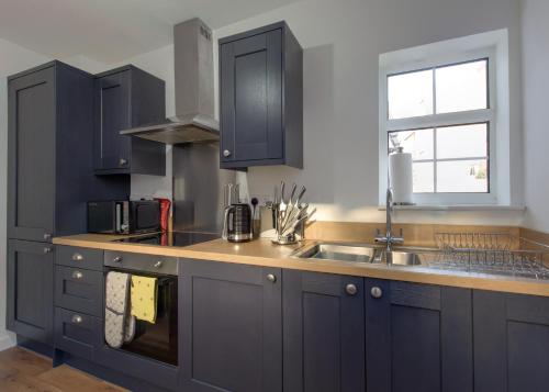 cocina con armarios azules, fregadero y ventana en Donington Cottage Apt 8, en Castle Donington