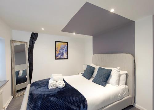 a bedroom with a large white bed with blue pillows at Donington Cottage Apt 8 in Castle Donington