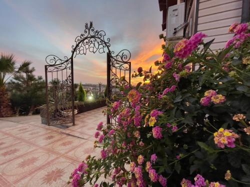 アドレルにあるPapaya Hotelの花の咲く庭園、夕日を背景に見える門