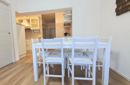a kitchen with a white table and white chairs at TERRAZZA sui MONTI in Andalo