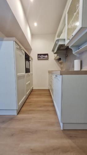 a kitchen with white cabinets and a white refrigerator at TERRAZZA sui MONTI in Andalo