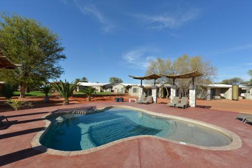 a swimming pool with chairs and a gazebo at Gondwana Kalahari Anib Lodge in Hardap