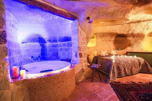 a bathroom with a bath tub in a stone room at Sinasos Palace Cave Hotel in Urgup