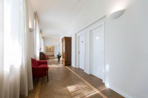a hallway with a red chair and white walls at Villaggio Narrante - Foresteria delle Vigne in Serralunga d'Alba