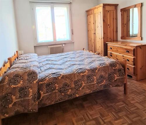 een slaapkamer met een bed en een houten dressoir bij CASA NELLY in Andalo
