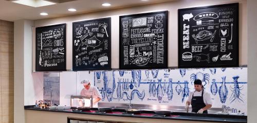 two chefs in a kitchen with a chalkboard wall at H10 Salauris Palace in Salou
