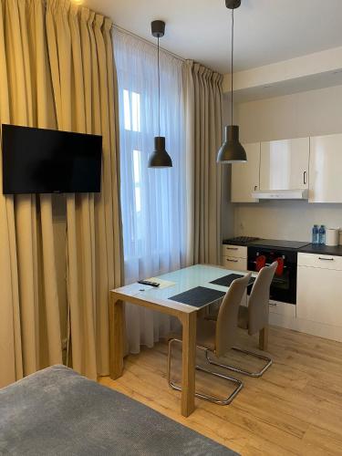 een keuken met een tafel en stoelen en een keuken met een televisie bij Apartament w centrum in Kościerzyna