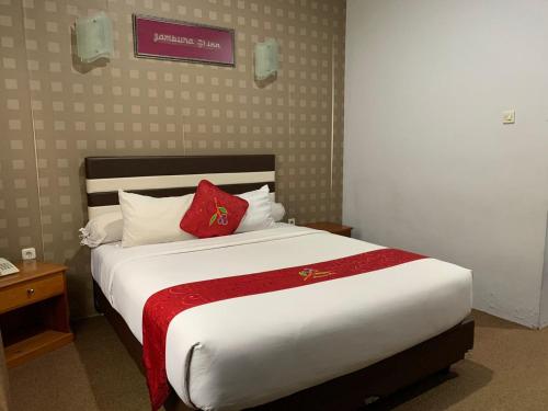 a bedroom with a large bed with a red pillow at Jambura Inn in Gorontalo