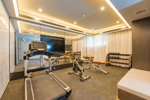a room with a gym with a treadmill and a television at Atour Hotel Langfang Railway Station in Langfang