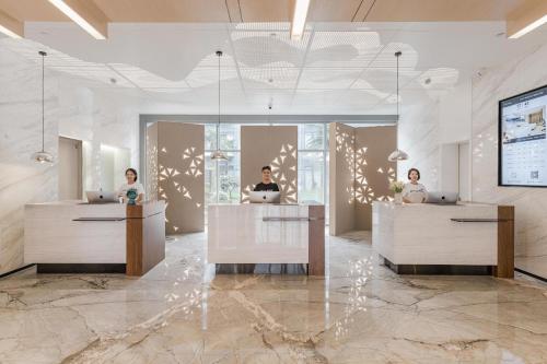 a lobby with three people sitting at reception desks at Atour Hotel Industrial Park Dongsha Lake in Suzhou
