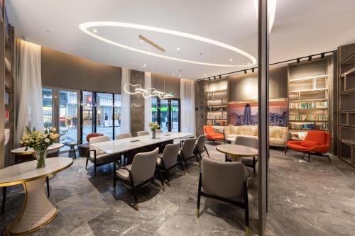 a dining room with tables and chairs and bookshelves at Atour Hotel Wuhan Guanggu Qingnianhui JinRongGang in Wuhan