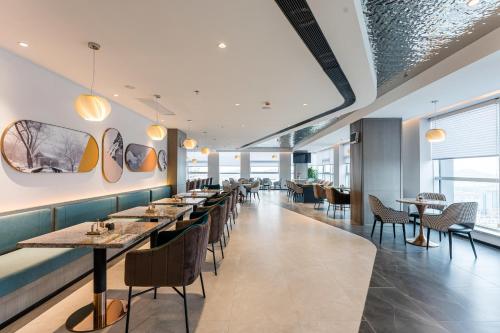 a restaurant with tables and chairs and windows at Atour Hotel Xuzhou CBD in Xuzhou