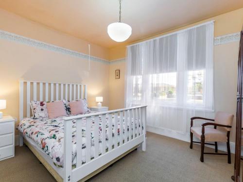 una culla bianca in una camera da letto con finestra di Lavender Cottage a Port Fairy