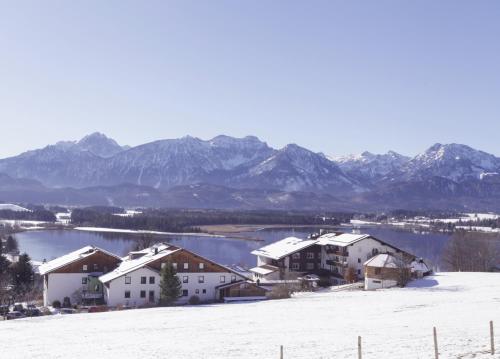 a village in the snow with mountains in the background at Biohotel Eggensberger in Füssen