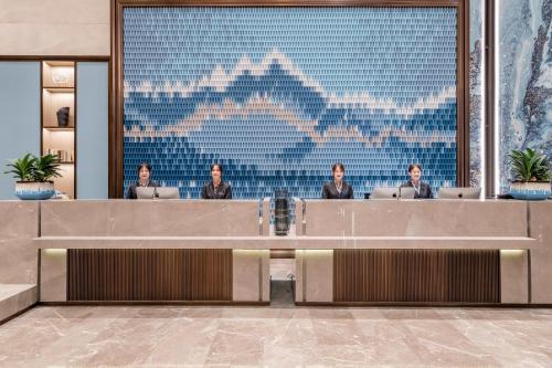 a lobby with three people sitting at desks in a building at Atour Hotel Nanjing Dongshan Cars 4S Park in Nanjing