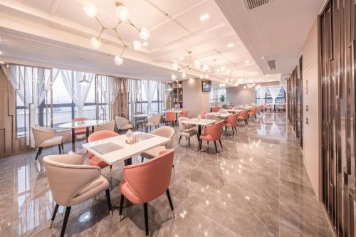 un restaurante con mesas, sillas y ventanas en Atour Hotel Luzhou Bubugao New World, en Luzhou