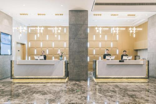 a lobby with three people sitting at their computers at Atour Hotel Xuzhou City Hall in Xuzhou