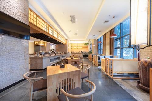 um restaurante com mesas, cadeiras e janelas em Atour X Hotel Yancheng Lingxiang Xinlong Road em Yancheng