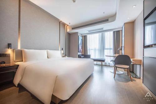 Atour Hotel Hengyang West Jiefang Road City Hall في هنغيانغ: سرير أبيض كبير في غرفة الفندق