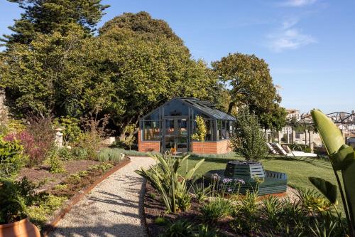 a garden with a glass house in the background at CASA CAMÉLIA in Porto