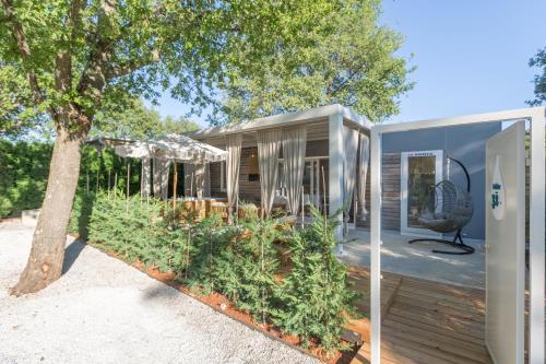 a tiny house with a tree in the yard at Polidor Camping Resort in Poreč