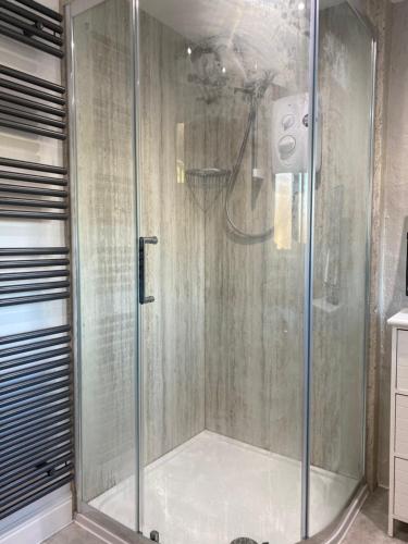a shower with a glass door in a bathroom at Tyddyn Bach Barn in Betws-y-coed
