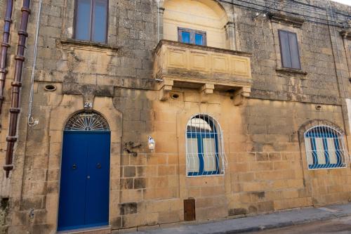 an old building with blue doors and windows at Centre Island Holiday Home with private pool and hot tub in Kerċem