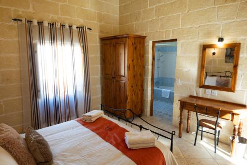 a bedroom with a bed and a desk and a mirror at Centre Island Holiday Home with private pool and hot tub in Kerċem