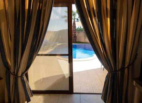 a sliding glass door with a view of a swimming pool at Centre Island Holiday Home with private pool and hot tub in Kerċem