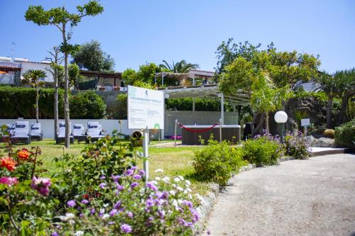 a garden with flowers and a sign in the grass at Hotel Parco Delle Agavi in Ischia