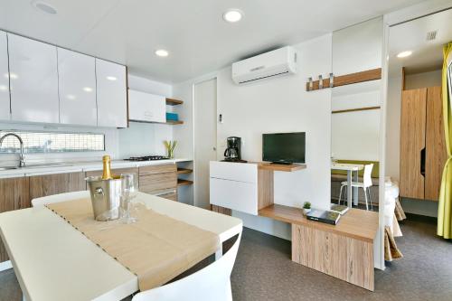 a kitchen with white cabinets and a dining table and a kitchen at Polidor Camping Resort in Poreč